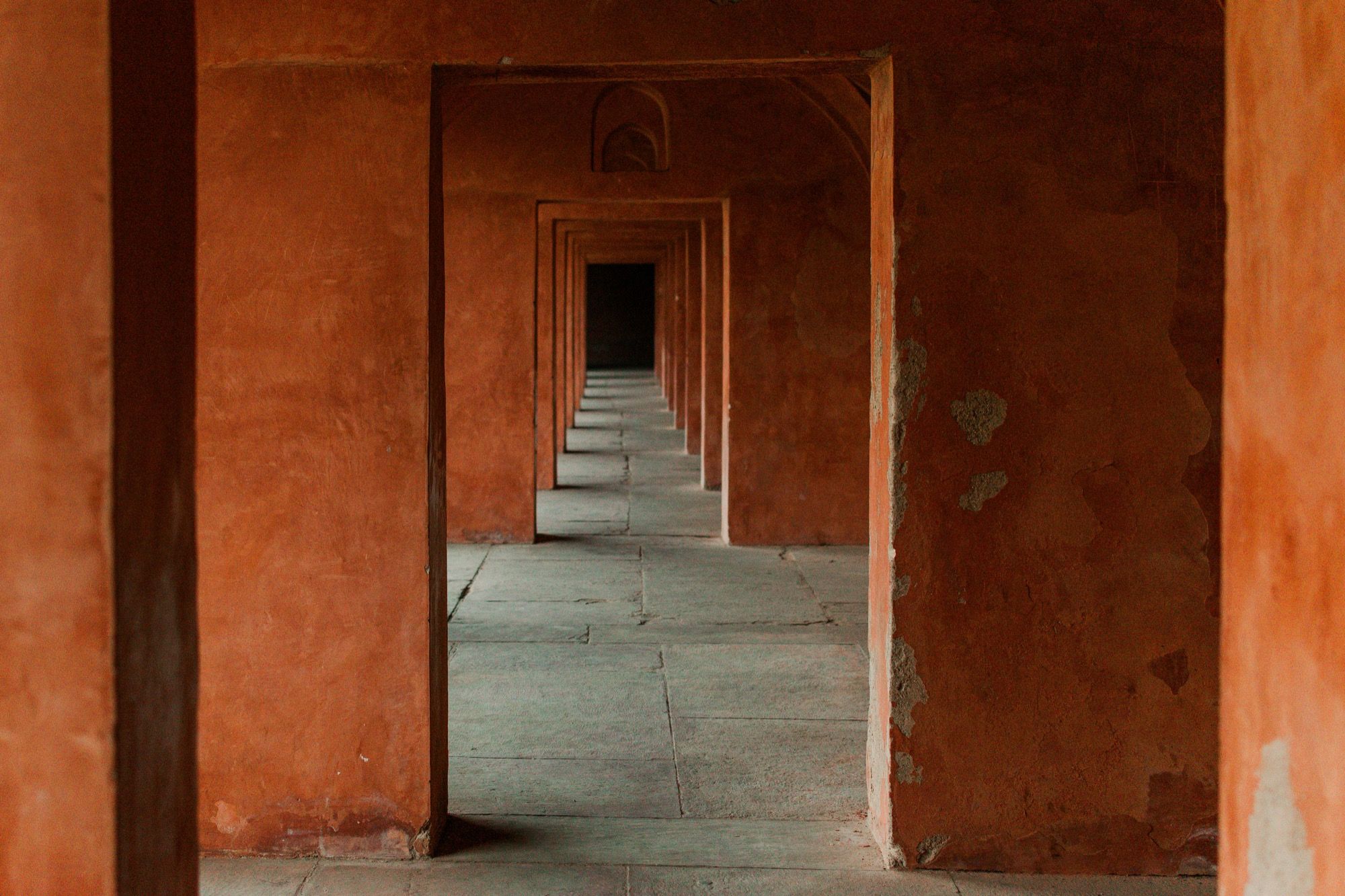 A sunlit corridor of terracotta archways receding into shadow
